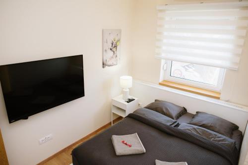 a living room with a flat screen tv and a couch at Lusso Apartman in Subotica