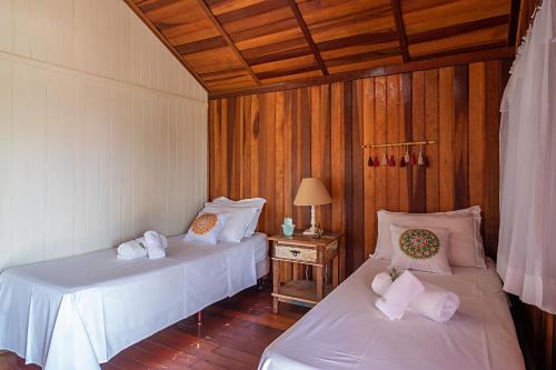 a room with two beds and a table with a lamp at Gaia Hospedagem Holística in Brotas