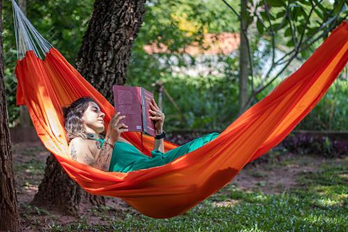a woman laying in a hammock reading a book at Gaia Hospedagem Holística in Brotas