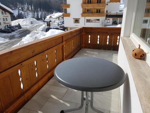 a stool on a balcony with a view of a snow covered mountain at Chasa Mezpra/Pfister-Jenal Nr. 1 - Ferienwohnung für 2-4 Personen in Samnaun
