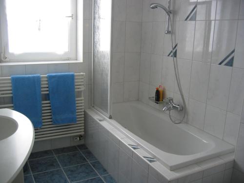 a bathroom with a tub and a shower with blue towels at Chasa Mezpra/Pfister-Jenal Nr. 1 - Ferienwohnung für 2-4 Personen in Samnaun