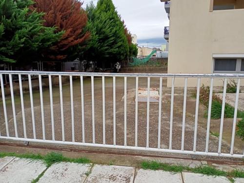 a white metal fence in front of a building at Semi-Basement 250m from Sea, Nea Chili in Alexandroupoli