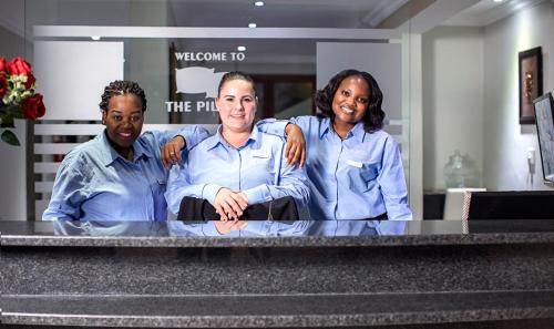Un groupe de trois personnes debout au-dessus d'un comptoir dans l'établissement The Pillows Suite, à Pretoria