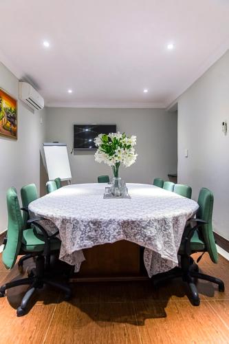 a table with green chairs and a vase of flowers on it at The Pillows Suite in Pretoria