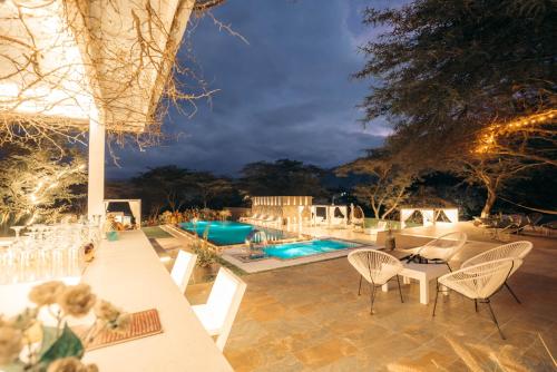 eine Terrasse mit Stühlen und einem Pool in der Nacht in der Unterkunft Tunas & Cabras Hotel in Ibarra