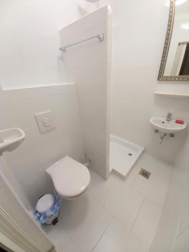a white bathroom with a toilet and a sink at Edelmann Panzió in Balatonakali