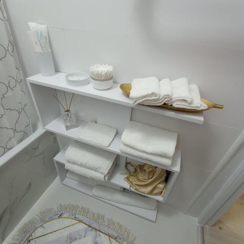 a bathroom with white shelves with towels on them at VIP Апартаменти in Dnipro