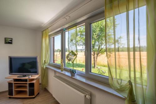 a room with a television and windows with a field at Ferienwohnung Bichler in Altötting