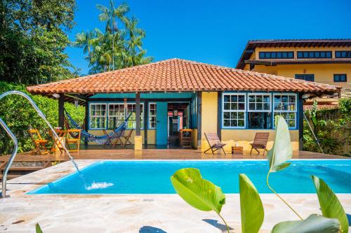 a house with a swimming pool in front of it at Casa do Pescador Camburi in Camburi