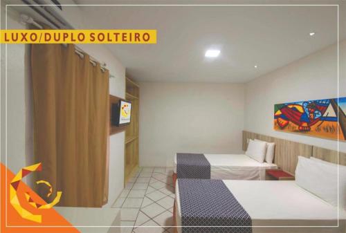 a hotel room with two beds and a sign at Netuanah Praia Hotel in João Pessoa