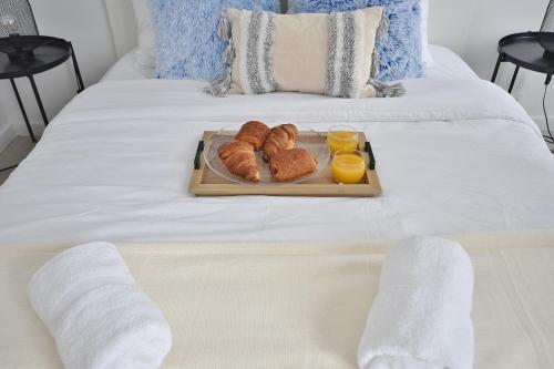 - un plateau de croissants et de jus d'orange sur un lit dans l'établissement Secret Garden - Duplex Moderne - Jardin - Netflix -, à Provins