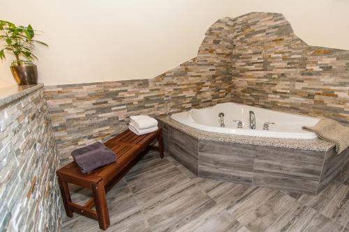 a bathroom with a tub and a wooden bench at Gingerbread House Inn - We Are Open - Winter, Spring, Summer and Fall in Wolfville