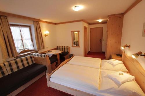 a bedroom with a bed and a couch and a table at Gästehaus Angerer in Reit im Winkl