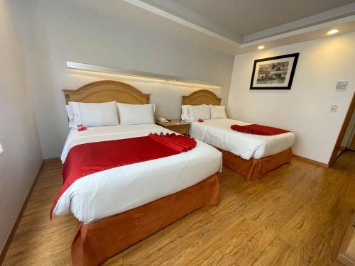 a hotel room with two beds with red sheets at Hotel Horizon & Convention Center in Morelia