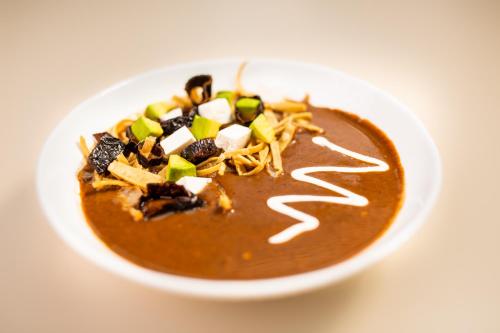 a bowl of soup with toppings on a white table at Hotel Horizon & Convention Center in Morelia
