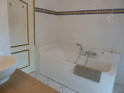 a white bath tub in a bathroom with a sink at Spacious Longere,heated swimming pool, idyllic setting, Southern Brittany, FR in Pluherlin