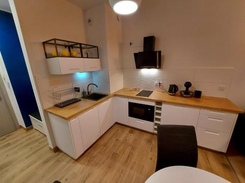 a kitchen with white cabinets and a wooden counter top at Allewidok in Jelenia Góra