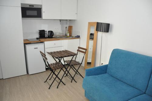 une cuisine avec un canapé bleu, une table et des chaises dans l'établissement Faubourg Saint Martin, à Paris