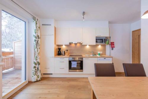 a kitchen with white cabinets and a table with chairs at Fuchs & Hase in Gasteig
