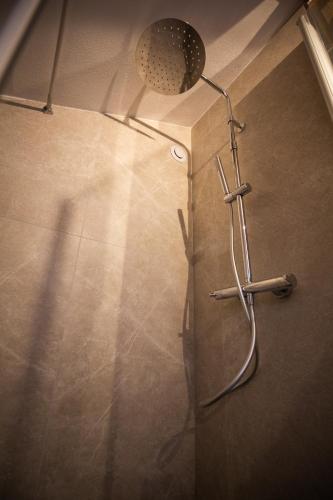 a shower in a bathroom with a light on the wall at Lärchenwirt Dolomites in San Nicolò di Comelico