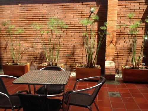 a table and chairs and a brick wall with potted plants at Hotel Vilar América in Bogotá
