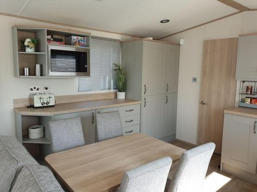 kuchnia z drewnianym stołem i krzesłami w obiekcie The Sea Breeze - 8 Berth Premium Caravan in Camber Sands w mieście Camber