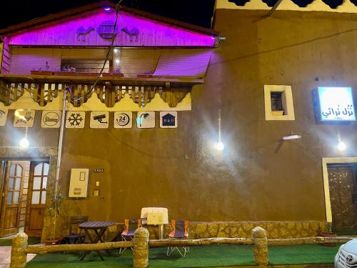 a building with a table and chairs in front of it at نُزُل تُراثي شقْراء Heritage Guesthouse Shaqra in Shaqra