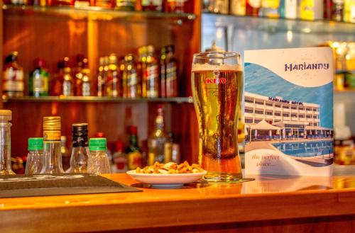 a glass of beer and a bowl of food on a bar at Mariandy Hotel in Larnaka