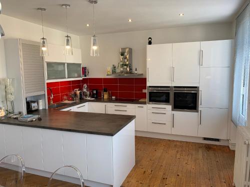 una cocina con armarios blancos y una pared roja en Appartement de charme 77 m2 proche commodités, en Chamalières