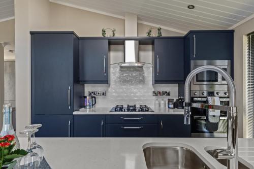 a kitchen with blue cabinets and a sink at Dewin Bach - Luxury Lodge, Hot Tub, Close to Beach in Penally