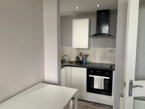 una cocina con armarios blancos y horno negro en Seaview one bedroom apartment in centre of Largs, en Largs