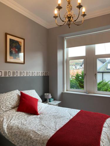 a bedroom with a bed with a red pillow and a window at Seaview one bedroom apartment in centre of Largs in Largs