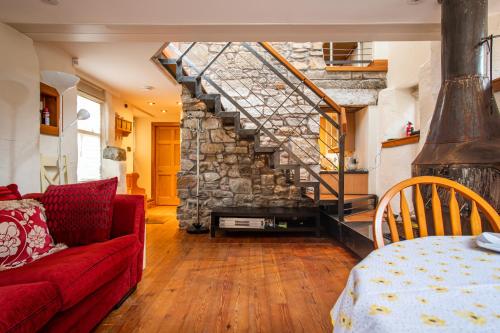 sala de estar con sofá rojo y pared de piedra en 2 Bedroom Characterful Semi-Detached House, Enviably Located with Balcony and Terrace en St Andrews