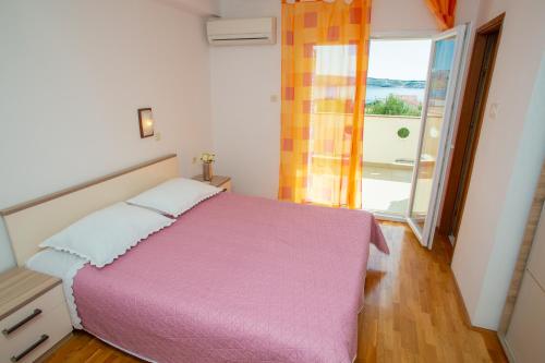 una camera con letto rosa e ampia finestra di Apartments Tonka a Kustići