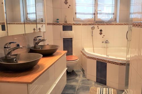 a bathroom with two sinks and a tub and a toilet at Appartement Lehnbach in Saas-Almagell