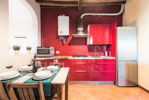 una cocina con armarios rojos y una mesa con sillas. en Hostly - La Pera Suite Apartment - 2 Bedrooms, Full Center, en Pisa