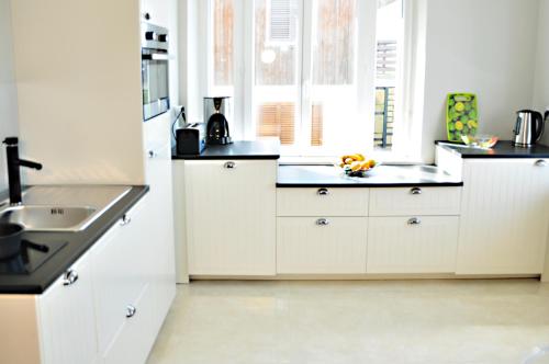 a kitchen with white cabinets and a sink at Résidence La Plage d'Or in Vierville-sur-Mer