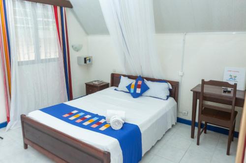 Schlafzimmer mit einem Bett, einem Schreibtisch und einem Bett in der Unterkunft Holidays Hotel in Mahajanga