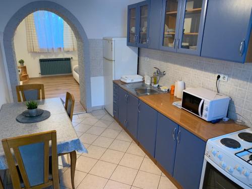 a kitchen with blue cabinets and a table with a microwave at Crystal Lakes Apartment in Plitvička Jezera