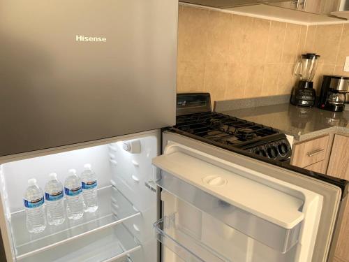 an open refrigerator with bottles of water in it at Departamento 2 habitaciones con vista a la piscina by EITA in Cancún