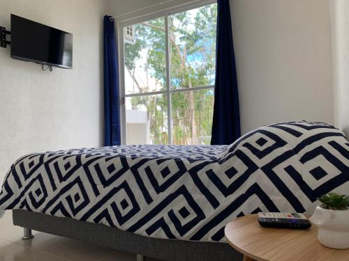 a bed with a black and white blanket and a window at Departamento 2 habitaciones con vista a la piscina by EITA in Cancún
