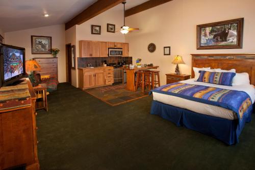 a bedroom with a large bed and a kitchen at Cottam's Lodge by Alpine Village Suites in Taos Ski Valley