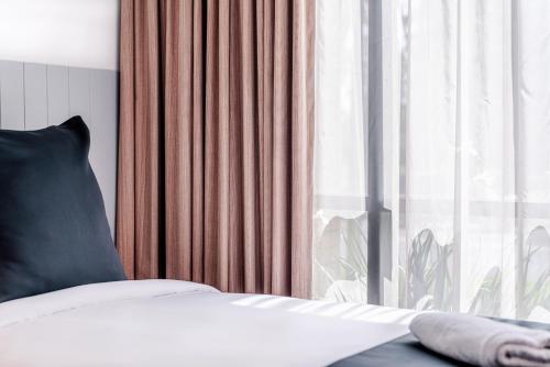 a bed with a black pillow and a window at The Select Inn Penrith in Penrith