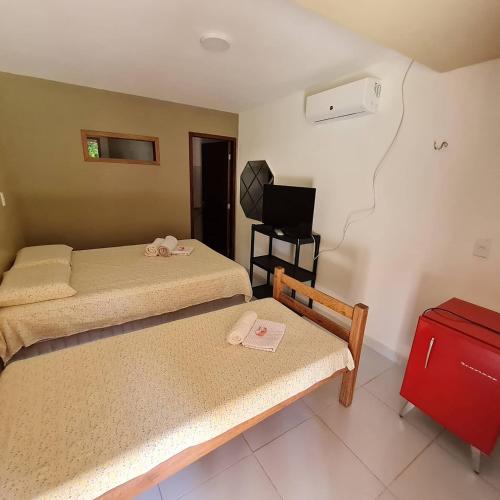 a bedroom with two beds and a red suitcase at Pousada Res. Belmont in Pirangi do Norte