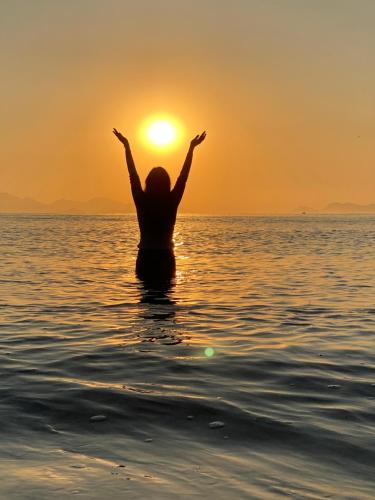a woman sitting in the water in the ocean at sunset at Casa Luz Paraty in Paraty