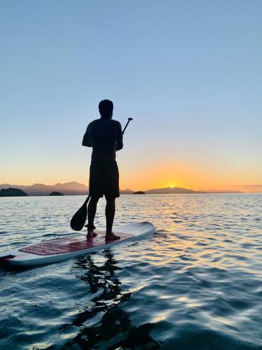 a man standing on a paddle board in the water at Casa Luz Paraty in Paraty