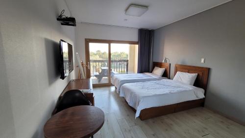 a hotel room with two beds and a table and a table sidx sidx at Oceantree House in Seogwipo