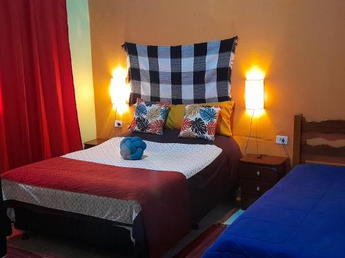 a bedroom with a bed with a blue stuffed animal on it at chales azaleia todos in São Bento do Sapucaí