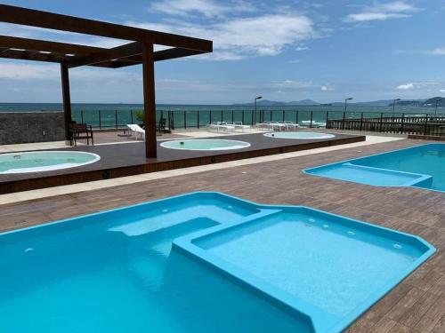 a group of three swimming pools on a deck with the ocean at Pé na areia - próximo ao Beto Carreiro in Barra Velha