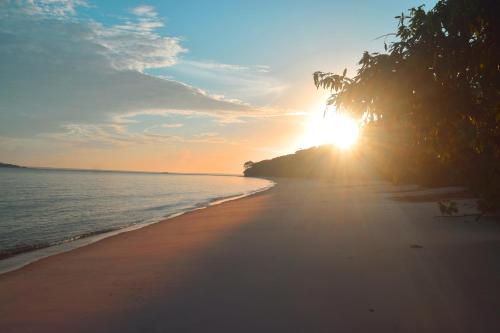 uma praia com o pôr do sol no horizonte em Pousada Grão em Belém